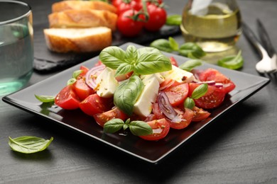 Photo of Tasty salad Caprese served on black table, closeup