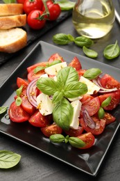 Photo of Tasty salad Caprese served on black table, closeup