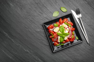 Photo of Tasty salad Caprese served on black table, flat lay. Space for text
