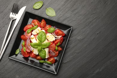 Photo of Tasty salad Caprese served on black table, flat lay. Space for text