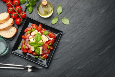 Photo of Tasty salad Caprese served on black table, flat lay. Space for text