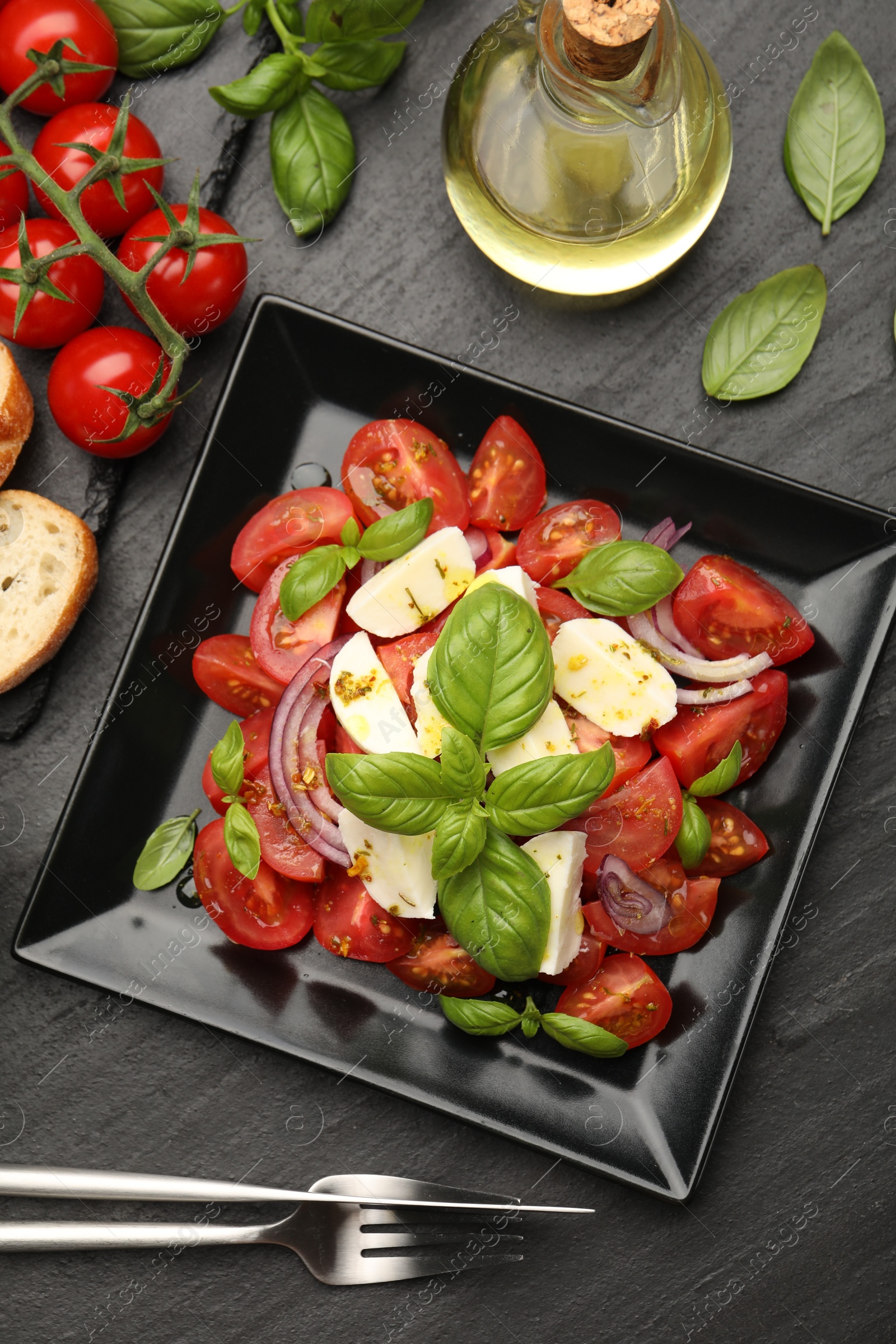 Tasty salad Caprese served on black table, flat lay Photo of Tasty salad Caprese served on black table, flat lay