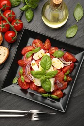 Photo of Tasty salad Caprese served on black table, flat lay
