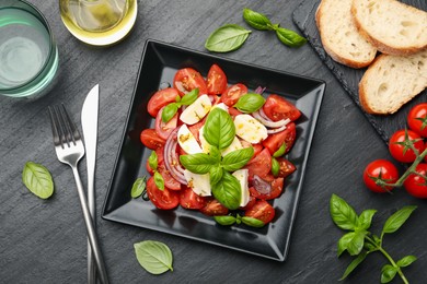 Photo of Tasty salad Caprese served on black table, flat lay