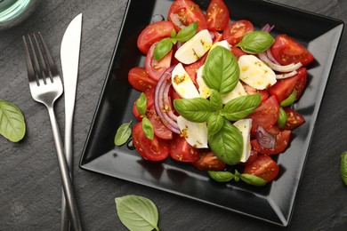 Photo of Tasty salad Caprese served on black table, flat lay
