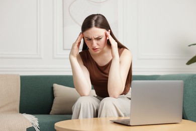 Photo of Woman suffering from headache on sofa at home
