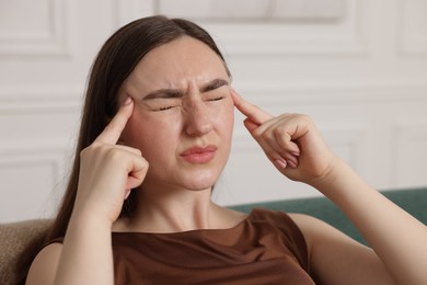 Photo of Young woman suffering from headache at home