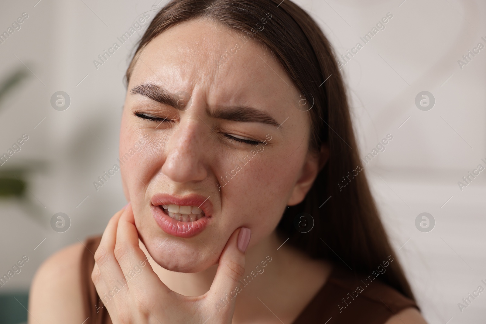 Photo of Young woman suffering from toothache at home