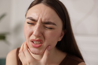Photo of Young woman suffering from toothache at home