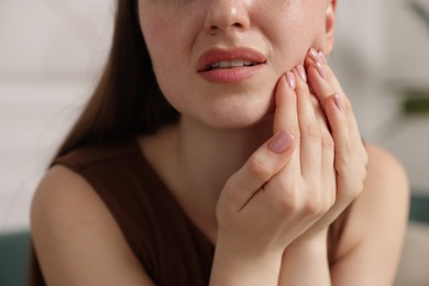 Photo of Woman suffering from toothache at home, closeup