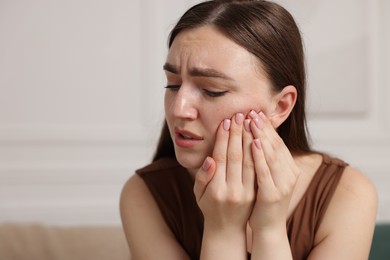 Photo of Woman suffering from toothache at home, space for text