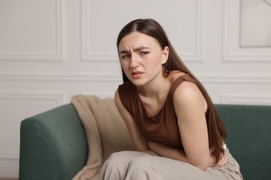 Photo of Woman suffering from abdominal pain on sofa at home