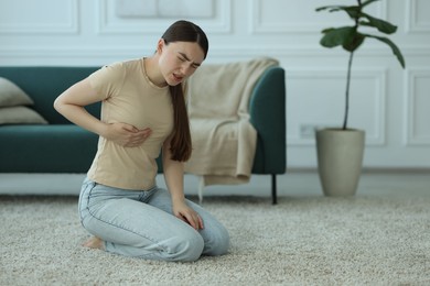 Photo of Woman suffering from chest pain at home, space for text
