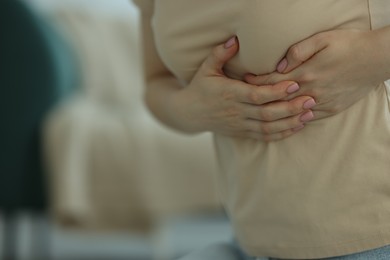Photo of Woman suffering from chest pain at home, closeup. Space for text
