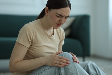 Photo of Woman suffering from knee pain at home