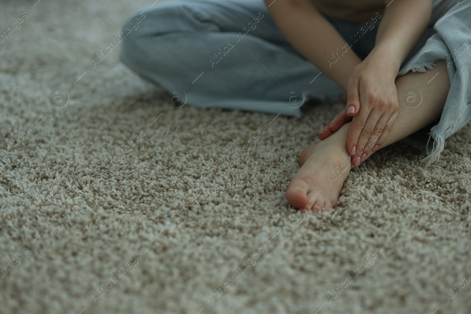 Photo of Woman suffering from foot pain on floor at home, closeup. Space for text