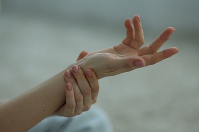 Photo of Woman suffering from wrist pain on floor at home, closeup