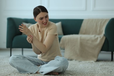 Photo of Woman suffering from wrist pain on floor at home, space for text