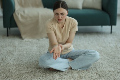 Photo of Woman suffering from wrist pain on floor at home