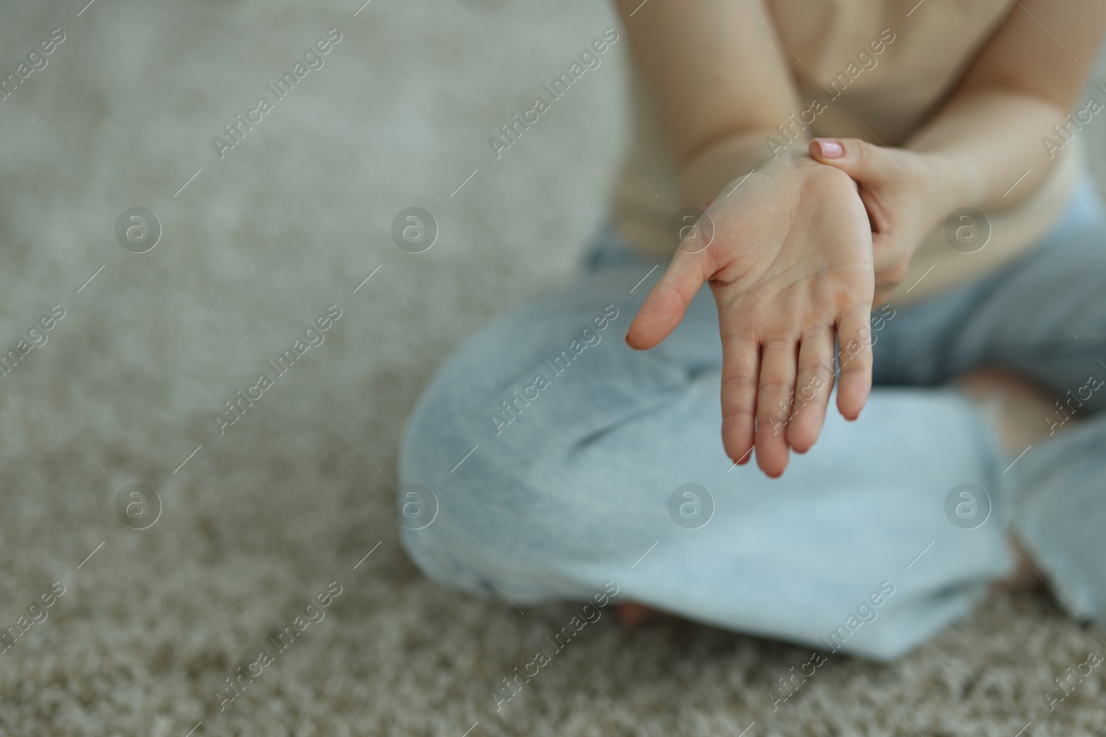 Woman suffering from wrist pain on floor at home, closeup. Space for text Photo of Woman suffering from wrist pain on floor at home, closeup. Space for text