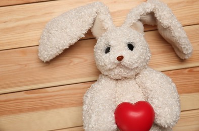 Photo of Pediatrics concept. Toy bunny and heart on wooden background, top view