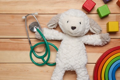 Photo of Pediatrics concept. Toys and stethoscope on wooden background, flat lay