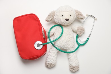 Photo of Pediatrics concept. Toy sheep with stethoscope and first aid kit on white background, top view