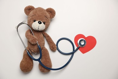 Photo of Pediatrics concept. Toy bear with stethoscope on white background, top view