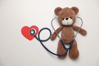 Photo of Pediatrics concept. Toy bear with stethoscope on white background, top view