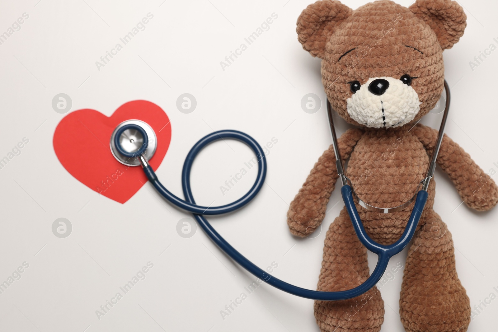 Photo of Pediatrics concept. Toy bear with stethoscope on white background, top view