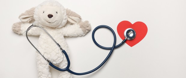 Photo of Pediatrics concept. Toy sheep with stethoscope on white background, top view