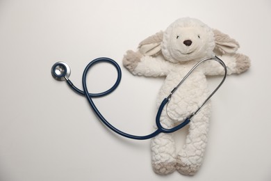 Photo of Pediatrics concept. Toy sheep with stethoscope on white background, top view
