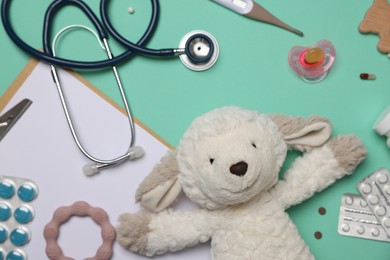 Photo of Pediatrics concept. Toy sheep with stethoscope, thermometer, clipboard and pills on turquoise background, flat lay
