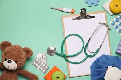 Photo of Pediatrics concept. Toy bear with stethoscope, thermometer and pills on turquoise background, flat lay