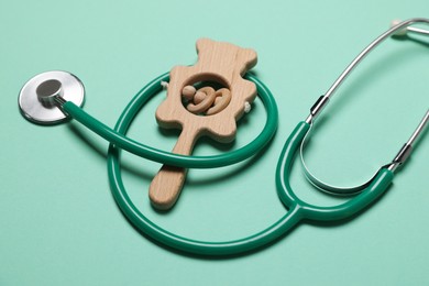 Photo of Pediatrics concept. Stethoscope and toy on turquoise background, closeup