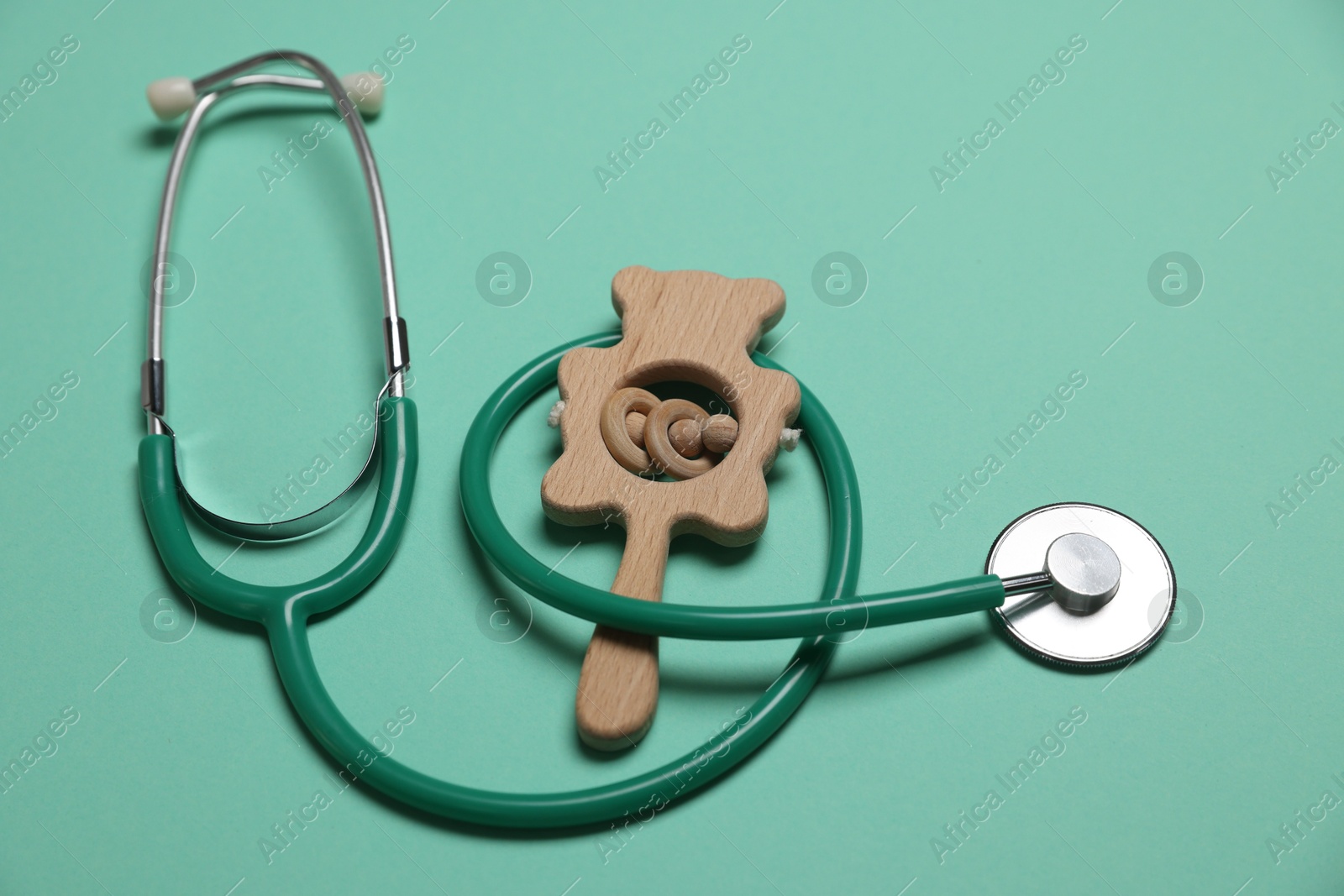 Pediatrics concept. Stethoscope and toy on turquoise background, closeup Photo of Pediatrics concept. Stethoscope and toy on turquoise background, closeup