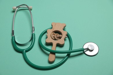 Photo of Pediatrics concept. Stethoscope and toy on turquoise background, closeup