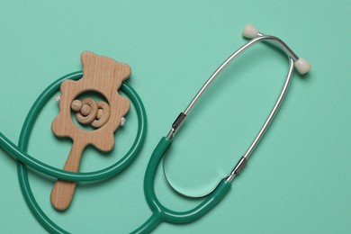 Photo of Pediatrics concept. Stethoscope and toy on turquoise background, top view