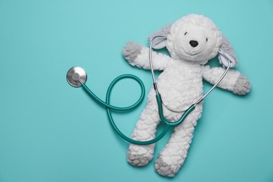 Photo of Pediatrics concept. Toy sheep with stethoscope on turquoise background, top view
