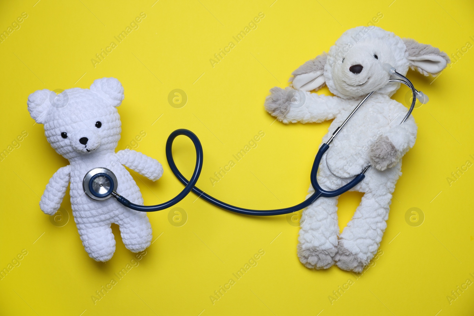 Photo of Pediatrics concept. Toy sheep and bear with stethoscope on yellow background, top view