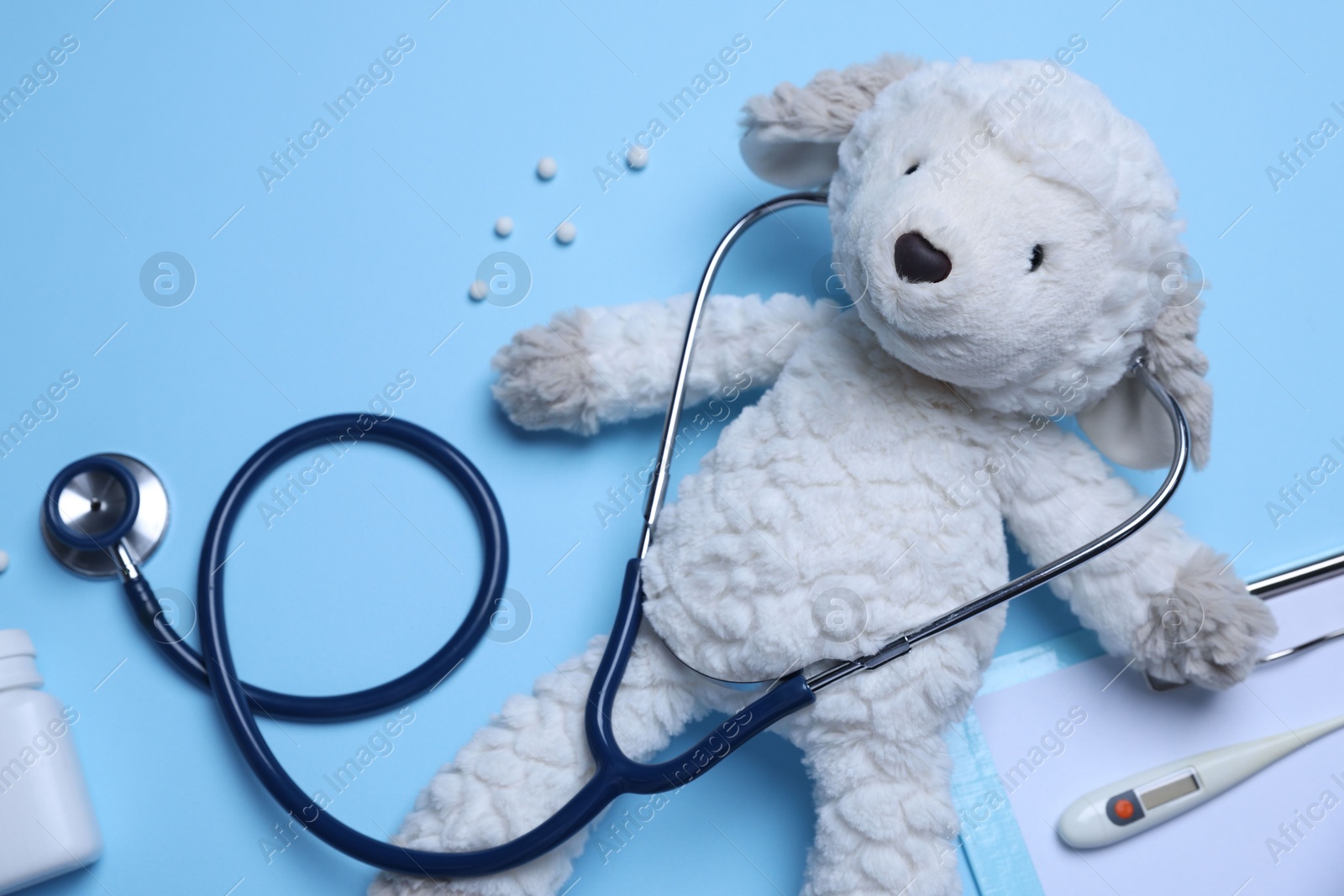 Pediatrics concept. Toy sheep with stethoscope and pills on light blue background, flat lay Photo of Pediatrics concept. Toy sheep with stethoscope and pills on light blue background, flat lay