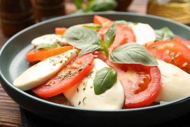 Photo of Tasty salad Caprese with mozzarella, tomatoes, basil and spices on table, closeup