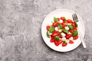 Photo of Tasty salad Caprese with mozzarella, tomatoes, basil and spices on grey table, top view. Space for text