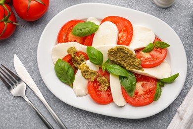 Photo of Tasty salad Caprese served with pesto sauce on grey table, flat lay