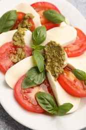 Photo of Tasty salad Caprese with mozzarella, tomatoes, basil and pesto sauce on table, closeup