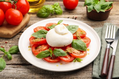 Photo of Tasty salad Caprese served with pesto sauce on wooden table, closeup