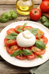 Photo of Tasty salad Caprese served with pesto sauce on wooden table, closeup
