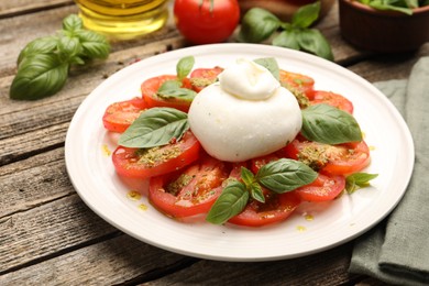 Photo of Tasty salad Caprese served with pesto sauce on wooden table, closeup