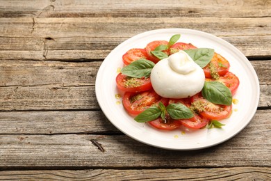 Photo of Tasty salad Caprese with mozzarella, tomatoes, basil and pesto sauce on wooden table, closeup. Space for text