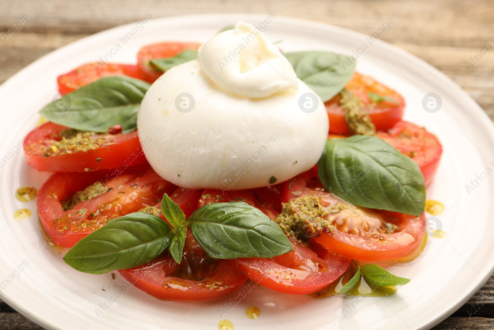 Photo of Tasty salad Caprese with mozzarella, tomatoes, basil and pesto sauce on table, closeup